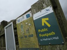 A wooden sign, covered in lichen, pointing to Hadrian's Wall